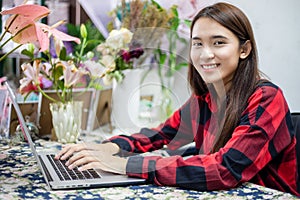 Asian women florists using notebook for working and smiling in flower shop