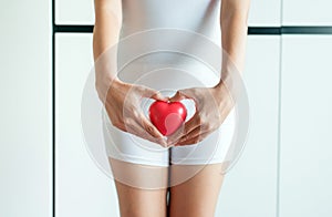 Asian woman hands holding red heart model on crotch with leucorrhoea