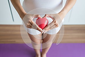 Asian woman hands holding red heart model on crotch with leucorrhoea photo