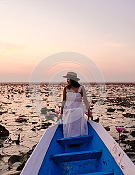 Asian women with a hat in a boat at the Red Lotus Sea full of pink flowers in Udon Thani Thailand.