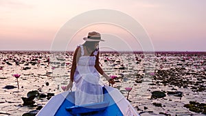 Asian women with a hat in a boat at the Red Lotus Sea full of pink flowers in Udon Thani Thailand.