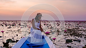 Asian women with a hat in a boat at the Red Lotus Sea full of pink flowers in Udon Thani Thailand.