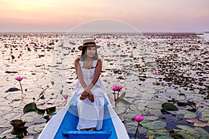 Asian women with a hat in a boat at the Red Lotus Sea full of pink flowers in Udon Thani Thailand.