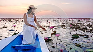 Asian women with a hat in a boat at the Red Lotus Sea full of pink flowers in Udon Thani Thailand.