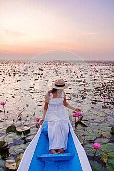 Asian women with a hat in a boat at the Red Lotus Sea full of pink flowers in Udon Thani Thailand.