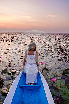 Asian women with a hat in a boat at the Red Lotus Sea full of pink flowers in Udon Thani Thailand.