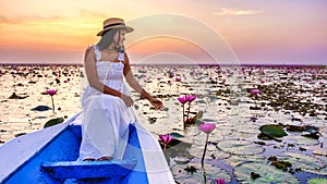 Asian women with a hat in a boat at the Red Lotus Sea full of pink flowers in Udon Thani Thailand.