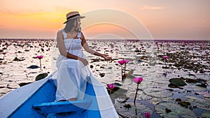 Asian women with a hat in a boat at the Red Lotus Sea full of pink flowers in Udon Thani Thailand.