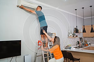 asian woman helping partner fixing airconditioner photo