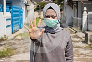 Asian women in hijab wear masks to protect and show stopped hand