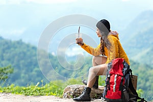 Asian women hiker or traveler with backpack adventure sitting and drinking ice coffee relax and rest on the mountain outdoor for d