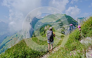 Asian women hiking in the Swiss Alps mountains at summer vacation with a backpack and hiking boots