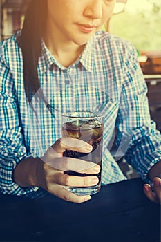 Asian women hold glass of soft drin in sunny day at restaurant,