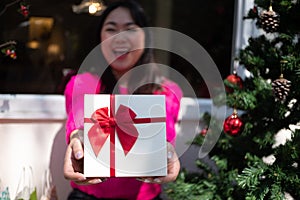 Asian women holding gift box smiling and happy with Christmas home decoration on the background