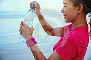 Asian women jogging workout on the beach in the morning. Relax with the sea walk and drinking water from the plastic bottles