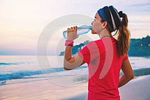 Asian women jogging workout on the beach in the morning. Relax with the sea walk and drinking water from the plastic bottles