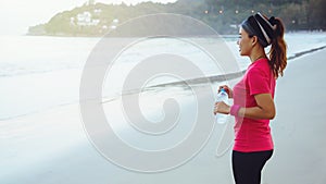 Asian women jogging workout on the beach in the morning. Relax with the sea walk and drinking water from the plastic bottles