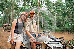 asian women leaning on the mans shoulder while standing beside the atv