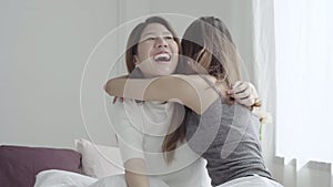 Asian women lesbian happy couple waking up in morning. Asian girls sitting on bed stretching in cozy bedroom at home.