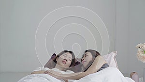 Asian women lesbian happy couple waking up in morning. Asian girls sitting on bed stretching in cozy bedroom at home.