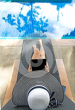 Asian Women lifestyle play laptop and relaxing near luxury swimming pool sunbath, summer day at the beach resort in the hotel.