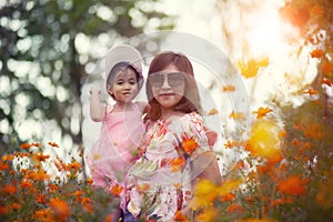 Asian woman and little girl happiness emotion in yellow cosmos flower blooming field