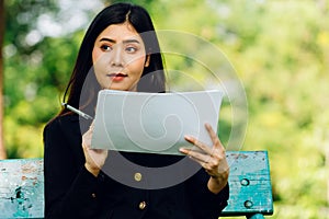 Asian women with long hair in work clothes Happily reading business papers in the park