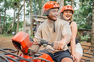 asian women looking at the camera while riding atv with her partner