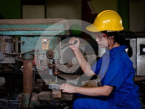 Asian women in mechanic uniforms are using power tools to drill metal bars in the factory