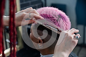 Asian woman with pink hair getting a haircut in a barbershop.