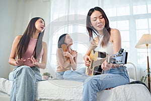 Asian women playing acoustic guitar and singing