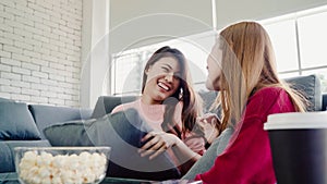 Asian women playing pillow fight and eating popcorn in living room at home, group of roommate friend enjoy funny moment while