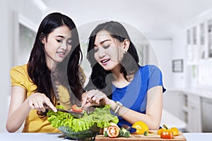 Asian women prepare salad together photo