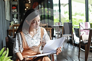 Asian women reading book and smiling and happy Relaxing in a coffee shop