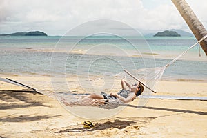 Asian women relaxing in hammock summer holiday on beach