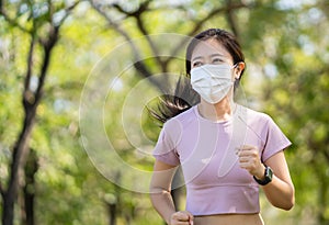 Asian women runners wears a Covid 19 protective mask and jogs in the garden in the morning. Health, sports and new normal concept