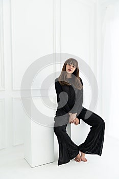 Asian women sit on white stool in  black lace fabric costume in white  backgroud / contrast  concept / fashion concept/ copy space