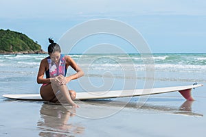 Asian women sitting on the beach she has a knee injury after working out by surfing in the sea