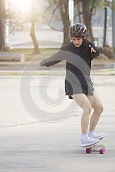 Asian women on skates board outdoors on beautiful summer day. Happy young women play surfskate at park on morning time. Sport