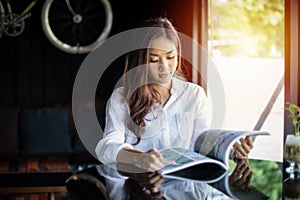 Asian women smiling and reading a book for relaxation at coffee shop