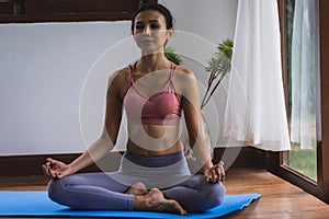 Asian women in sportwear sitting on Yoga mat and maditating and close her eyes in living room