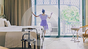 Asian women are staying in a hotel room and relax.Open the curtain and  door in the room looking to outside view.Travel in