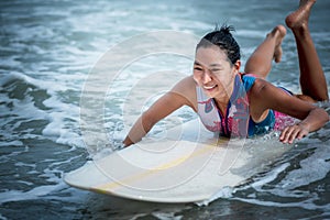 Asian women Surfboarding in the sea with small waves happily