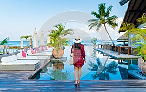 Asian women at a swimming pool at a luxury hotel, sunbed chair and umbrella