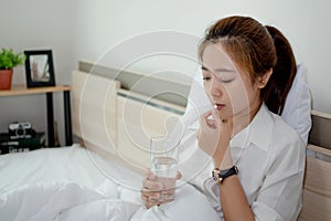 Asian women taking medication. She was sick in bed