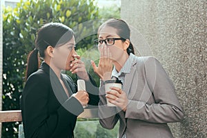 Asian women talking about office gossip