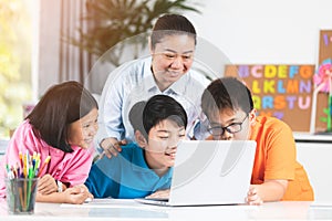 Teacher and Cute Asian children using laptop computer together.