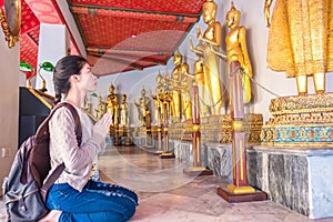 Asian women tourist backpack is worshiping the image of Buddha in holiday at wat pho Bangkok Thailand. It is a landmark and