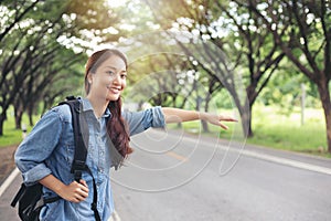 Asian women tourists and backpackers waiting car and Freedom traveler woman standing with raised arms at the roadside