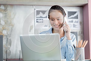 Asian women are using laptops and phoning in office photo